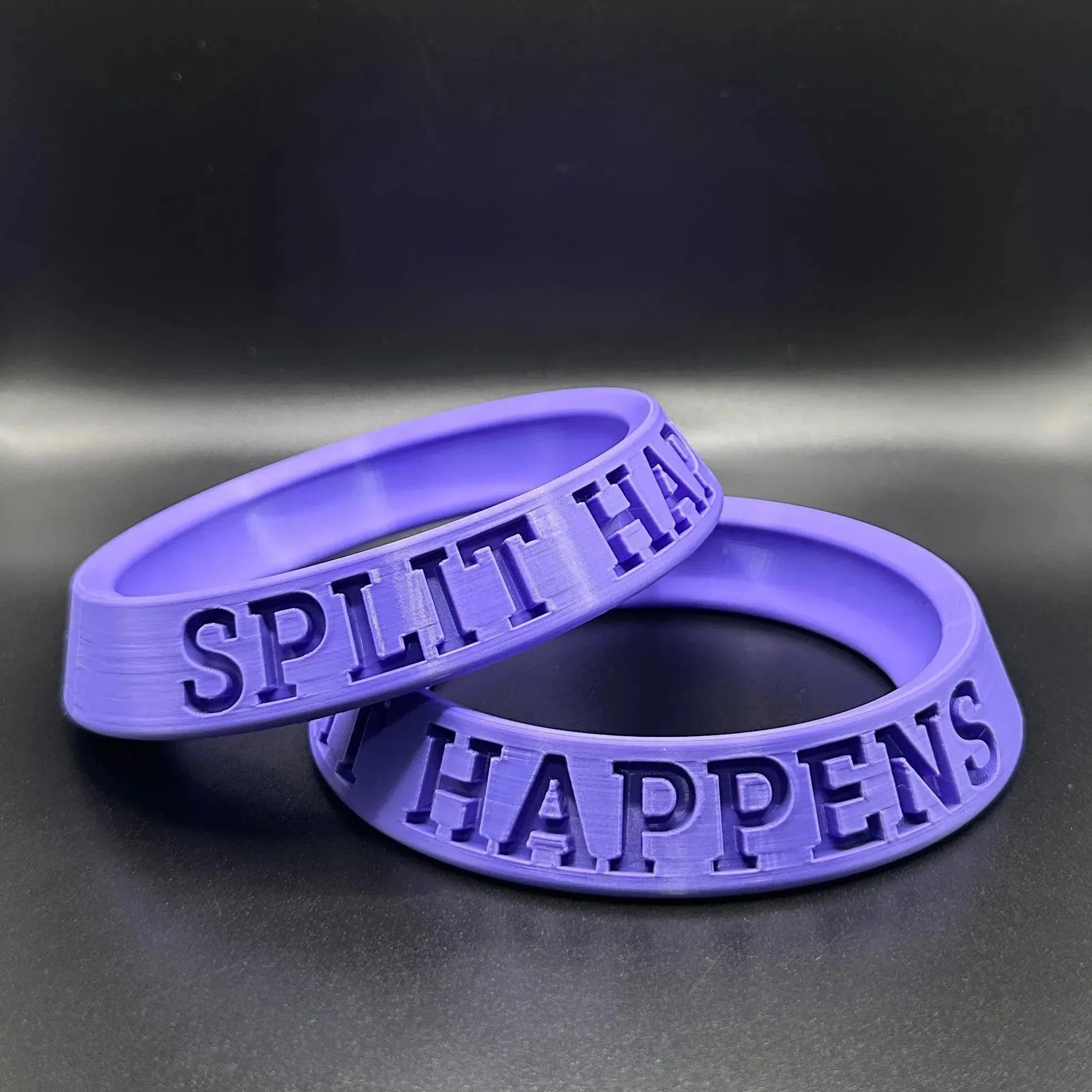 Two purple custom bowling ball holders with 'SPLIT HALF HAPPENS' text on a dark background