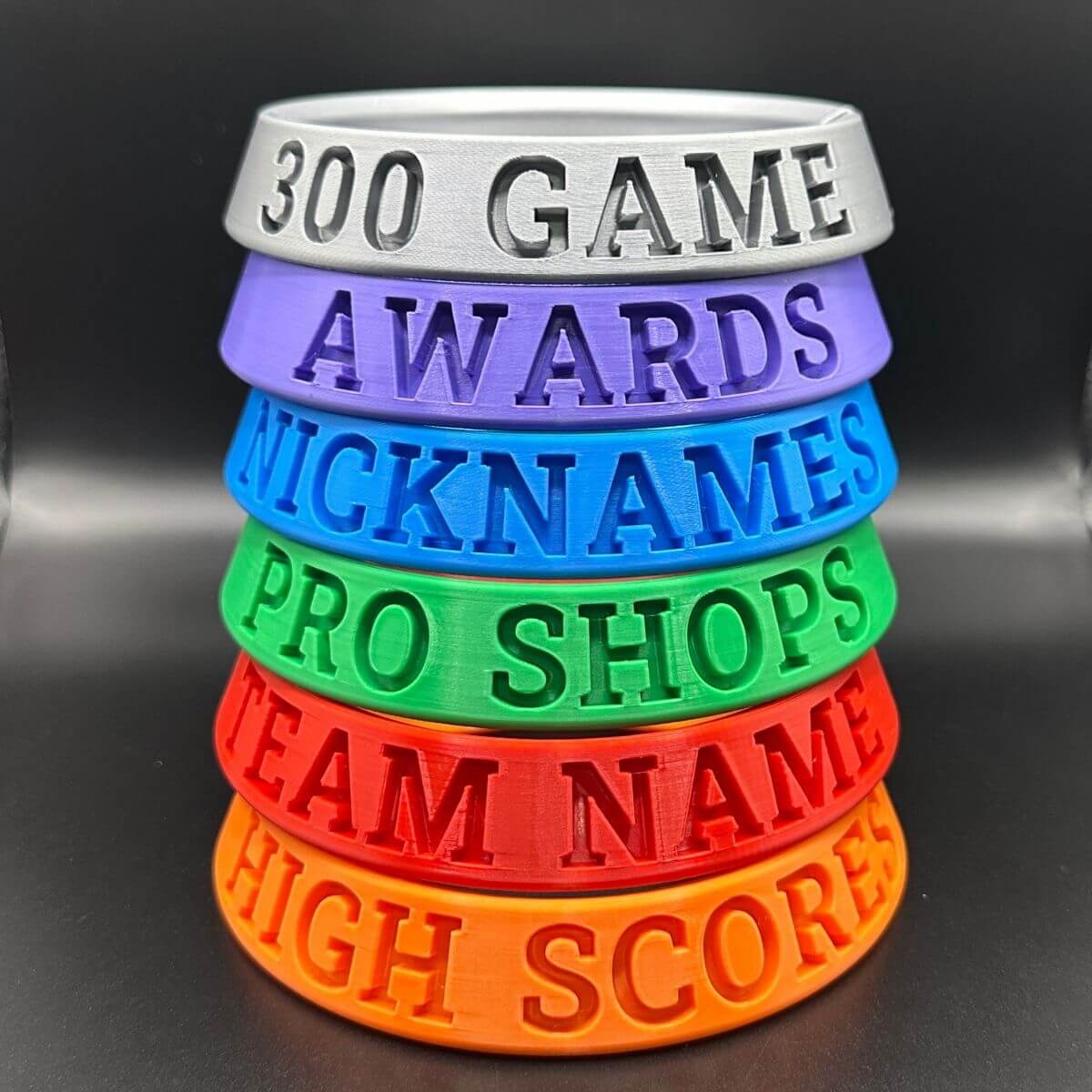 Stack of colorful silicone wristbands with text on a black background