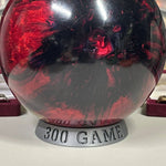 Bowling ball holder with red and black design on a white surface, featuring '300 Game' text.