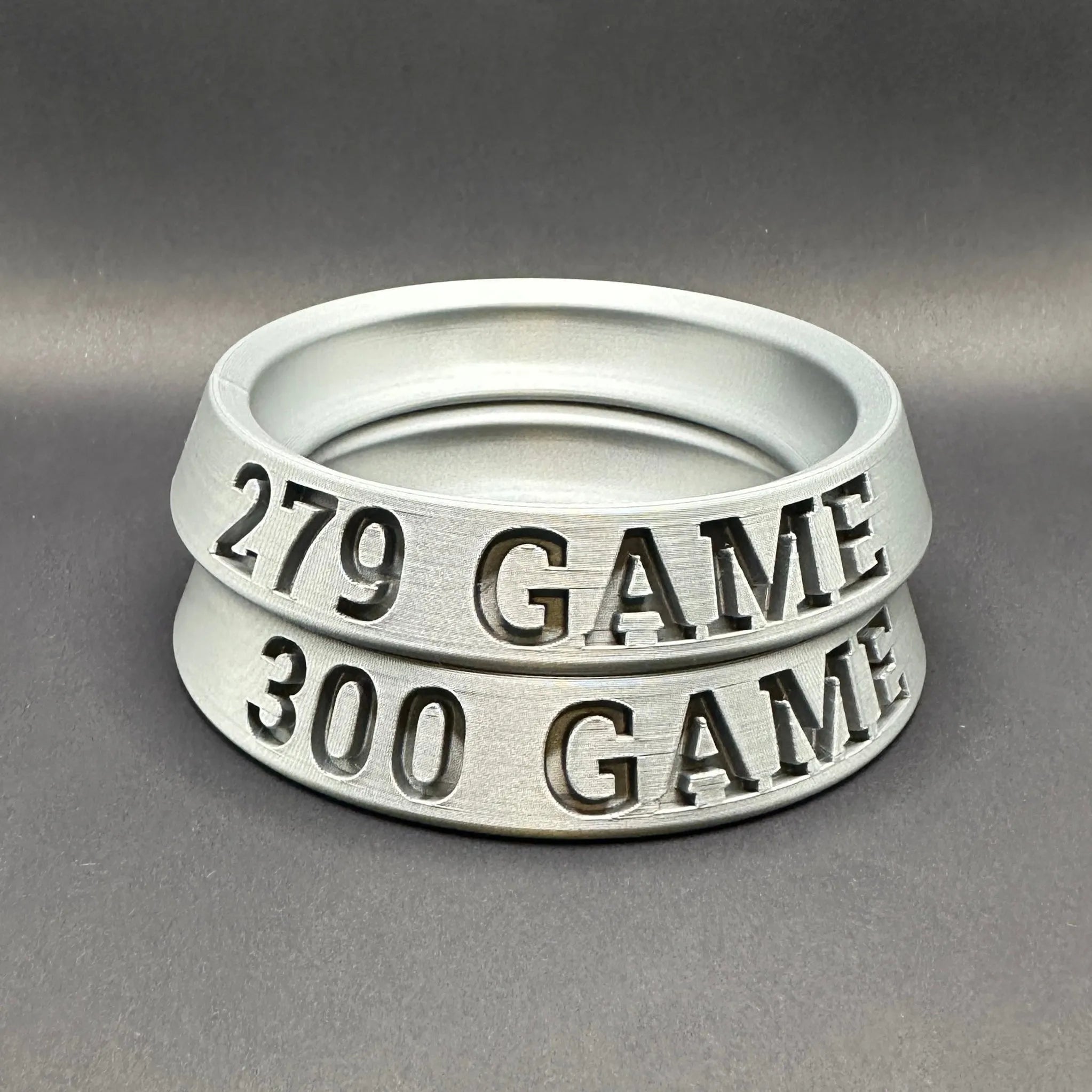 Two silver rings with engraved numbers and text on a gray background