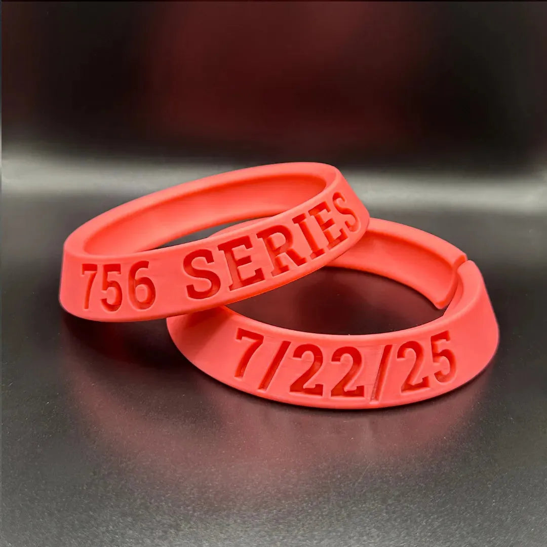 Two red wristbands with text on a reflective surface