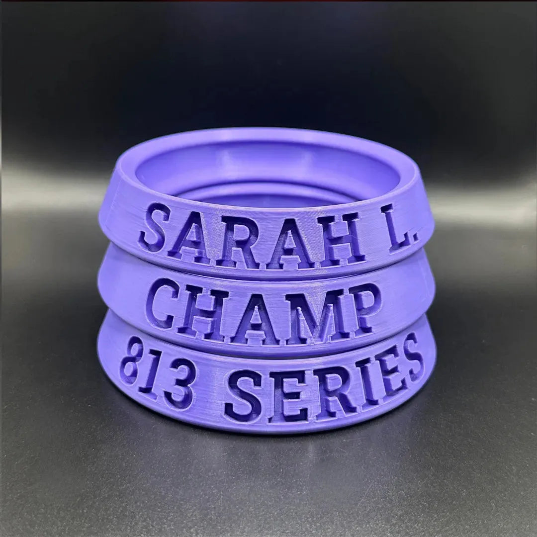 Stack of purple silicone rings with engraved text on a dark background