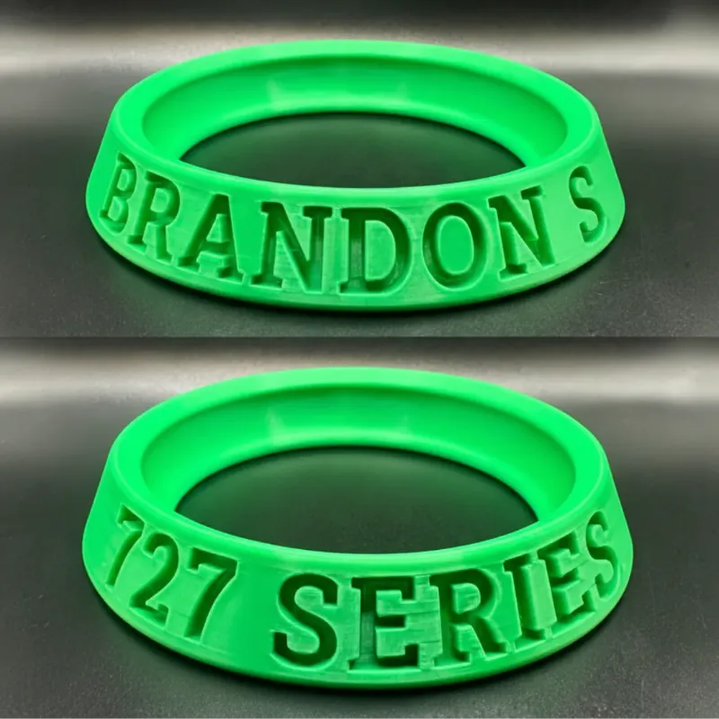 Two green rubber rings with embossed text on a metallic surface