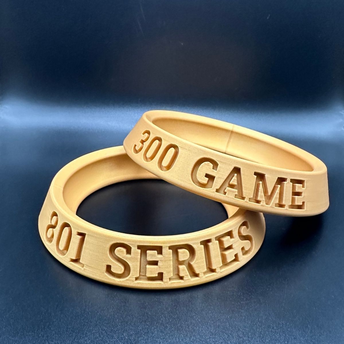 Two gold rings with engraved text on a blue background