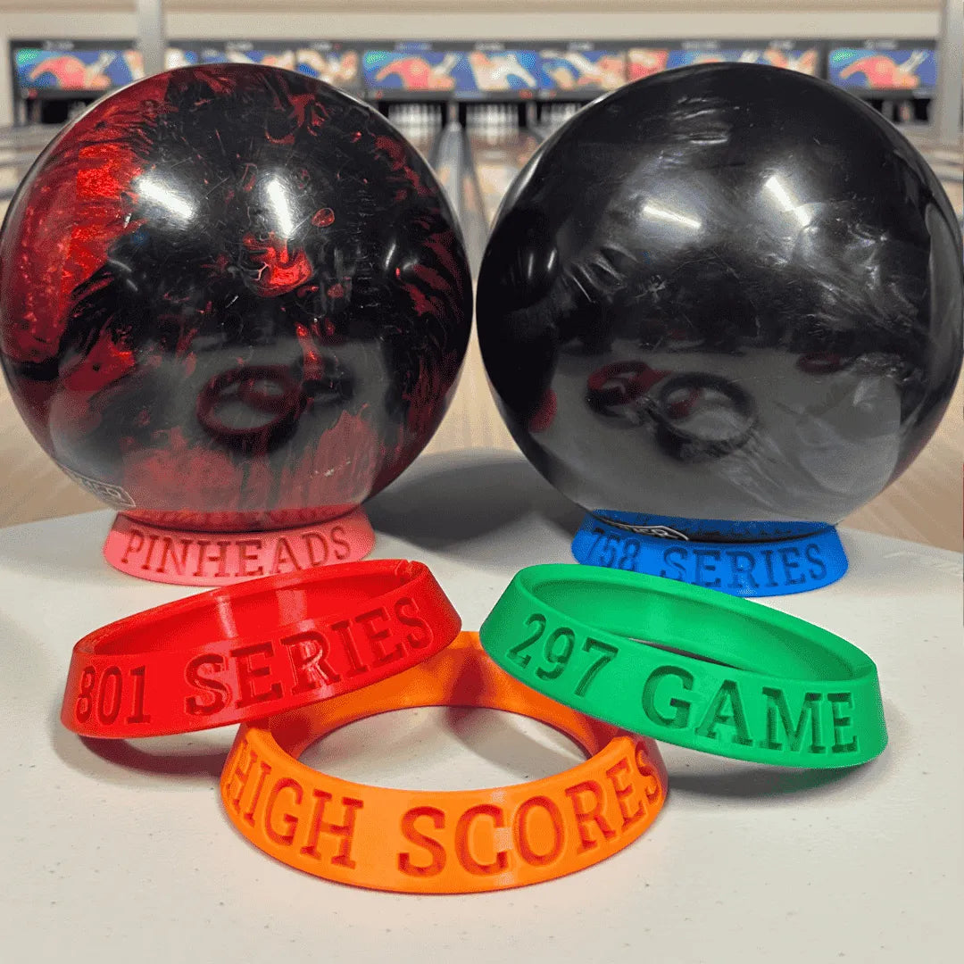Two large bowling balls and four colorful wristbands with text on a white surface.
