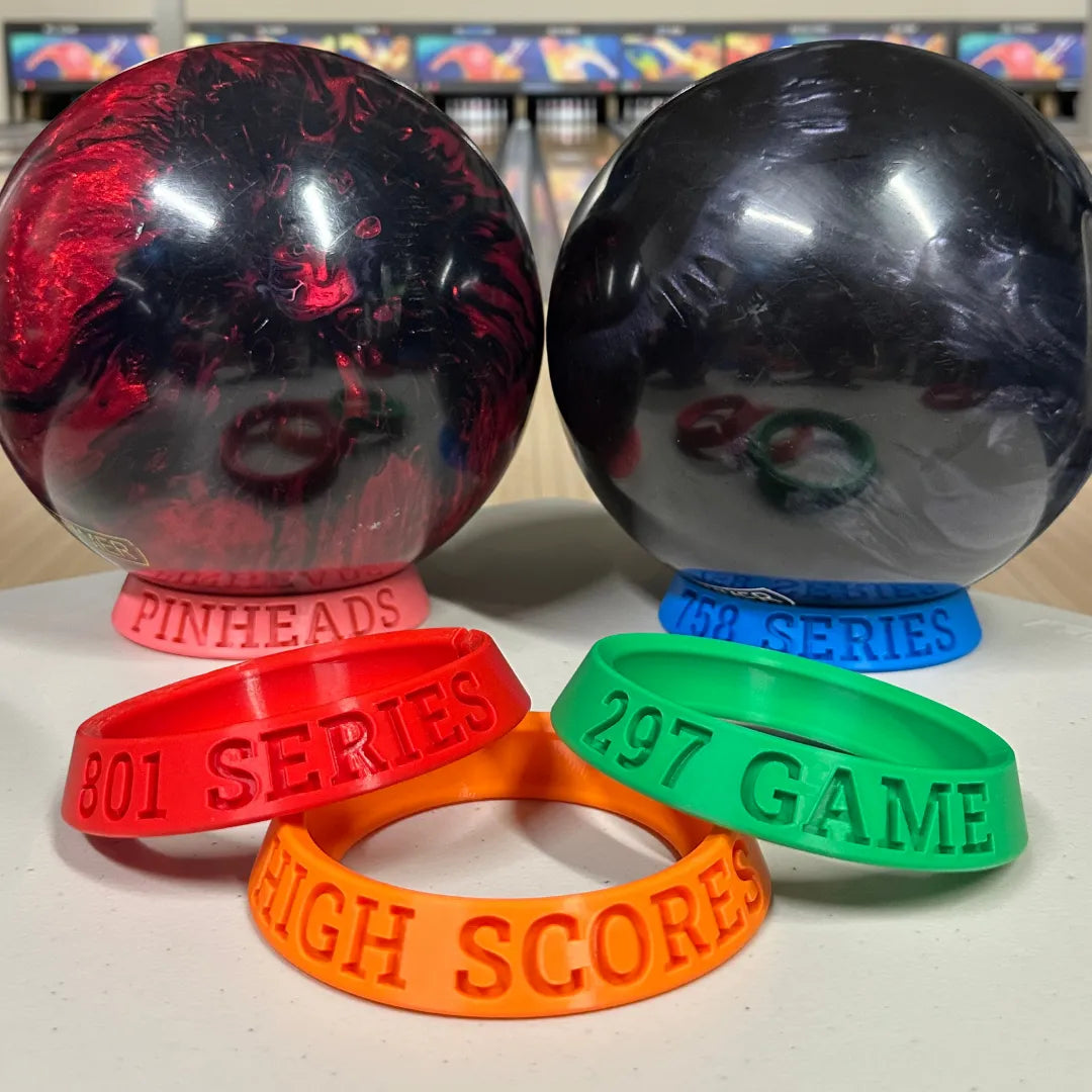 Two bowling balls and three colorful wristbands with text on a white surface.
